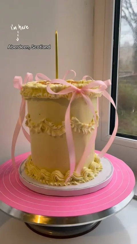 Tall pale yellow vintage cake with pink ribbon bows