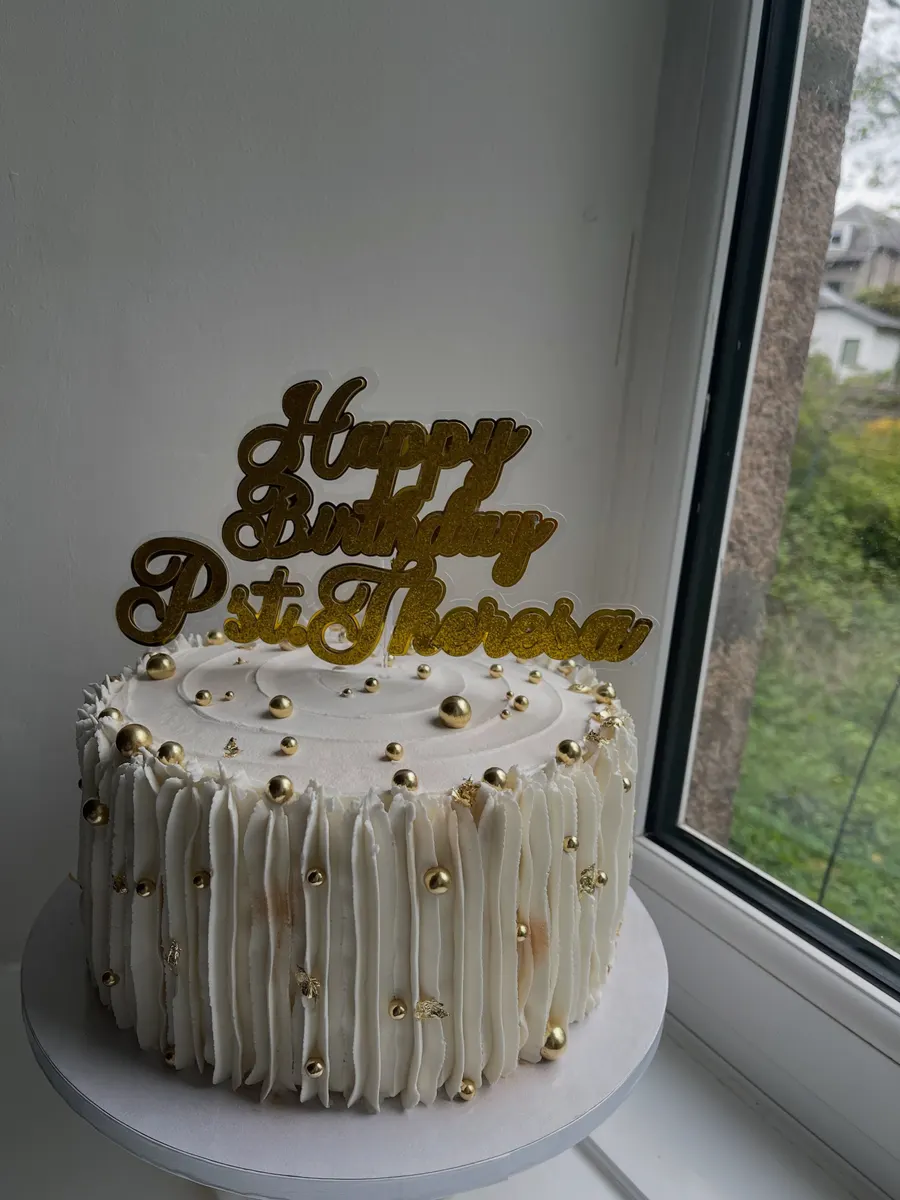 Cream cake with gold drip lines and a gold Happy Birthday topper