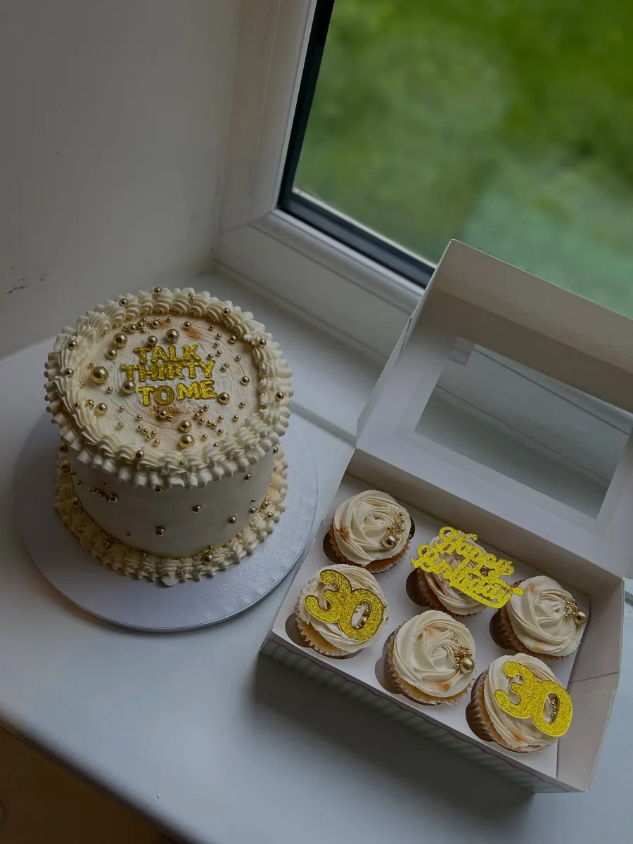 Cream and gold 30th birthday cake with a box of matching cupcakes