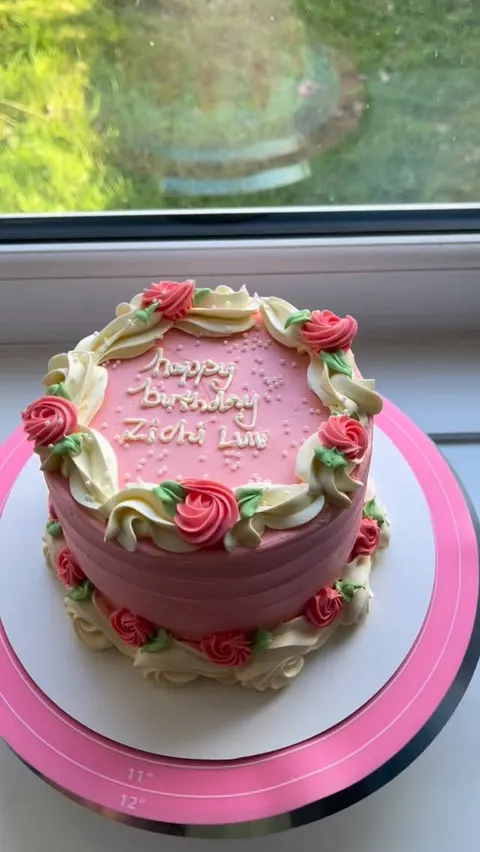 Pink cake piped with a ring of red and cream buttercream roses