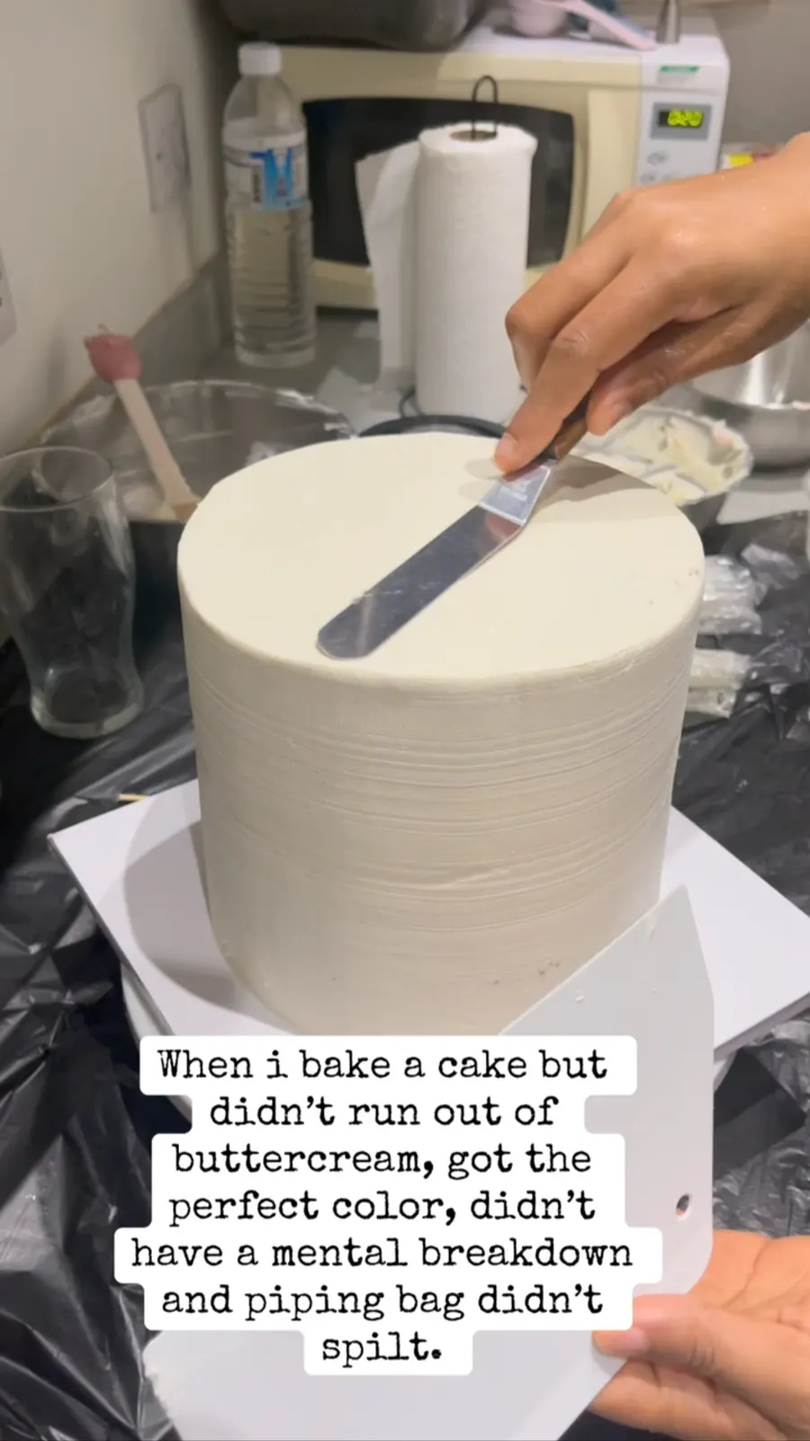 Smoothing buttercream on a tall cake